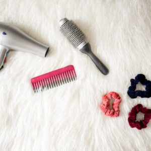 gray corded hair dryer and red comb